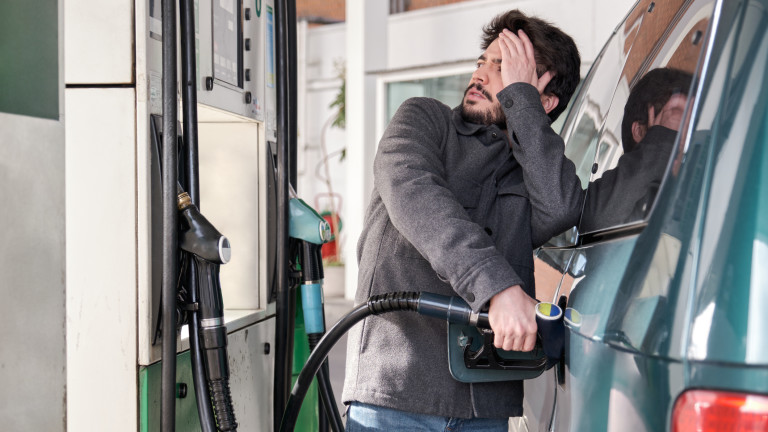 Young man refueling his vehicle while looking worried at the high gas prices.